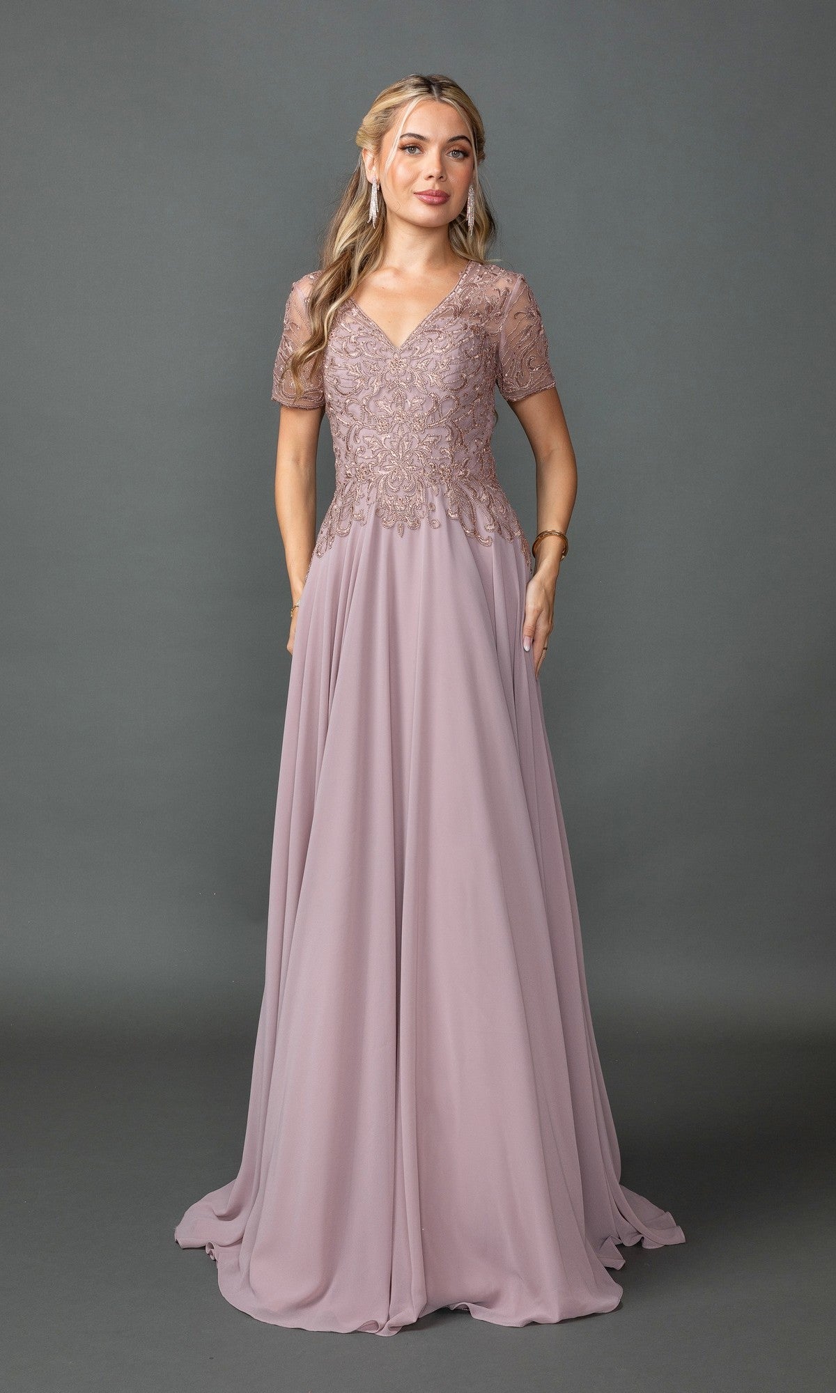 A woman poses against a gray background in a mauve Dancing Queen 4445 long formal dress, featuring short sheer lace sleeves and a fitted embroidered-lace bodice.